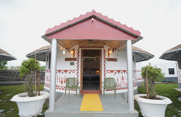 The Bhonga welcomes you with a traditional carved doorway, tribal art, and a calm verandah overlooking lush green surroundings.